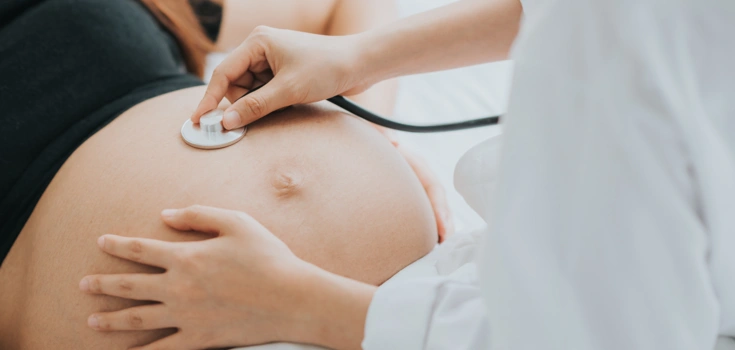 Bild von einer schwangeren Frau deren Bauch gerade von einer Ärztin abgehört wird