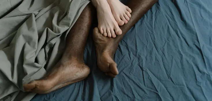 Füße eines Paares, die im Bett liegen